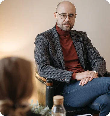Um homem de óculos e casaco ouve atentamente o seu interlocutor durante uma consulta individual